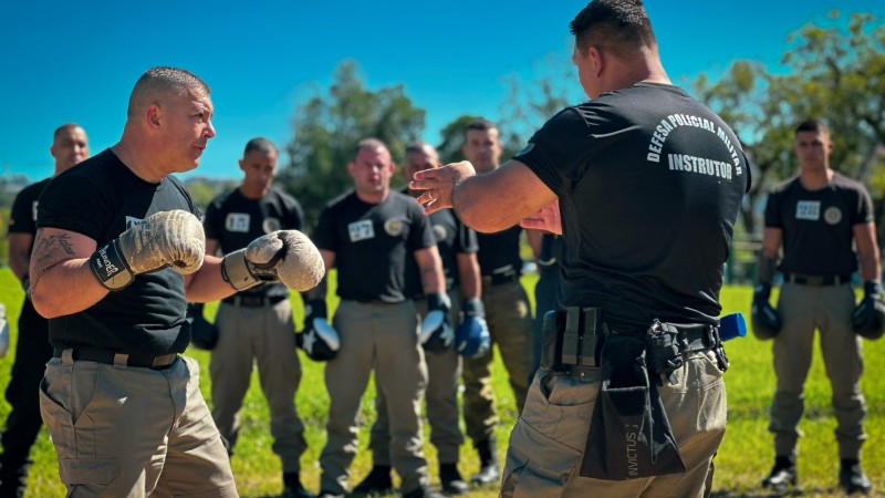 Foto mostra policiais militares praticando golpes durante o curso de Defesa Policial Militar a c&eacute;u aberto