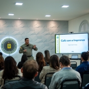Os Coron&eacute;is est&atilde;o em p&eacute; diante dos jornalistas que ocupam as cadeiras do audit&oacute;rio da sede da BM em Porto Alegre. H&aacute; uma tela de apresenta&ccedil;&atilde;o de slides e o s&iacute;mbolo da Institui&ccedil;&atilde;o ao centro da imagem. 