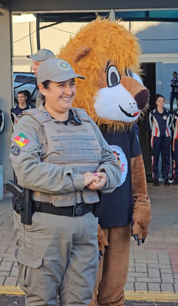 A PM aparece ao lado do mascote do Proerd, o leão Daren. 