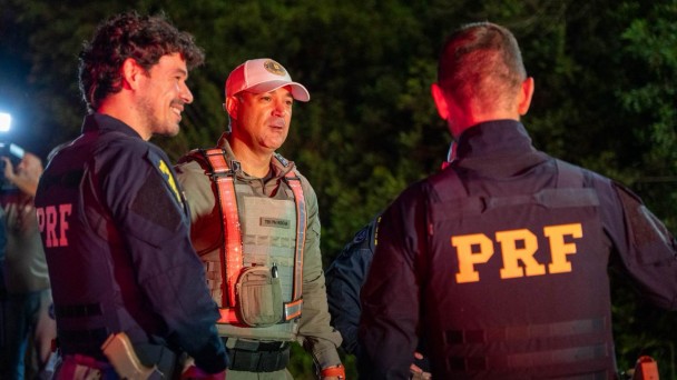 Foto mostra policial da Brigada Militar ao lado de dois policiais da Polícia Rodoviária Federal durante barreira durante a noite