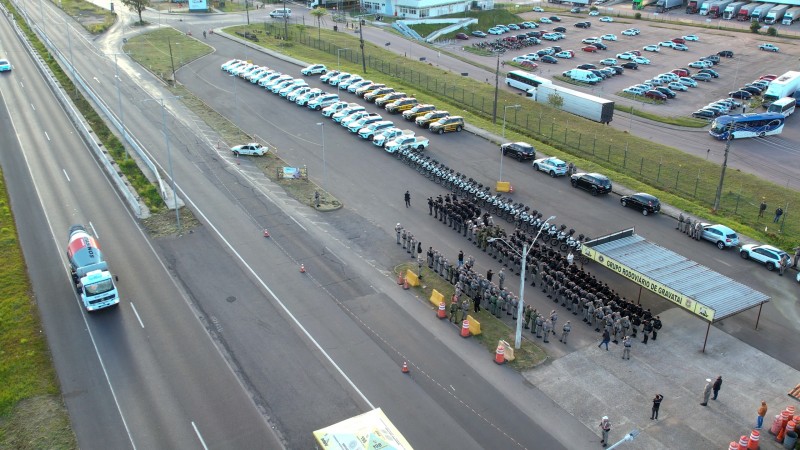 Imagem de drone mostra os policiais militares em forma, ao lado da rodovia RS-118