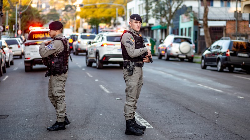 Foto mostra dois policiais militares parados na rua, durante uma barreira
