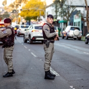Foto mostra dois policiais militares parados na rua, durante uma barreira