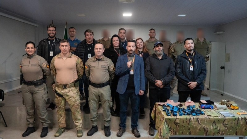 Foto mostra colegas da imprensa posando para a foto junto aos operadores do Bope dentro de um audit&oacute;rio.