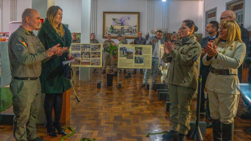 Imagem do desenlace da fita e abertura da exposi&ccedil;&atilde;o com a presen&ccedil;a do chefe do Estado-Maior da Brigada Militar, coronel PM &Aacute;lvaro Martinelli, da secret&aacute;ria-adjunta da Seguran&ccedil;a P&uacute;blica, delegada Adriana Regina da Costa, a Tenente-Coronel Amanda Martins Mondadori e a cantora F&aacute;tima Gimenez . 