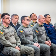 A imagem mostra militares estaduais da Brigada Militar e convidados sentados em cadeiras durante a solenidade dos 28 anos do Departamento de Pessoal e Finanças. Em primeiro plano, oficiais fardados acompanham atentamente a cerimônia em um auditório.