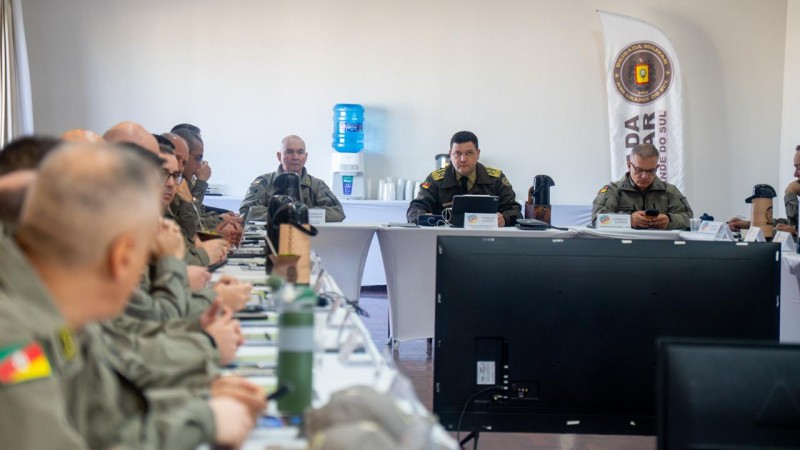 Imagem mostra coron&eacute;is reunidos em um audit&oacute;rio, sentados em uma grnade mesa disposta em formato retangular