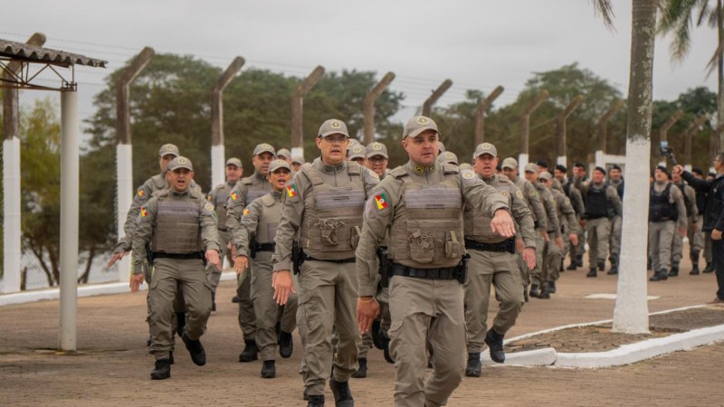 O efetivo de PMs atuantes na PEJ aparece saindo em marcha da sede da Penitenci&aacute;ria durante o ato simb&oacute;lico de entrega da gest&atilde;o &agrave; Pol&iacute;cia Penal. 